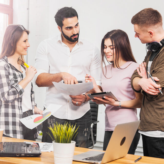 Team von Büroangestellten diskutiert Diagramme, Innenaufnahme in einem modernen Büro