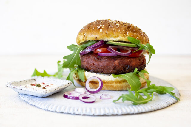 Ein Burger mit Pattie, Zwiebeln, Tomaten und Salat