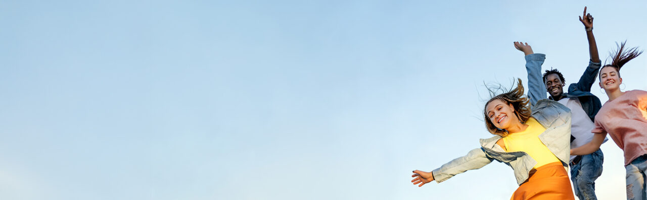 Glückliche Menschen springen vor blauem Himmel