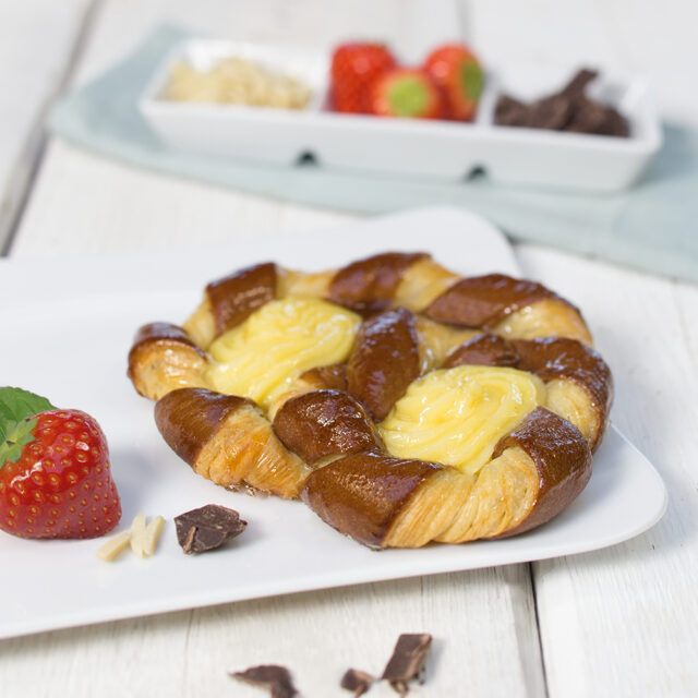 Geflochtenes Gebäck mit Vanillecreme auf weißem Teller