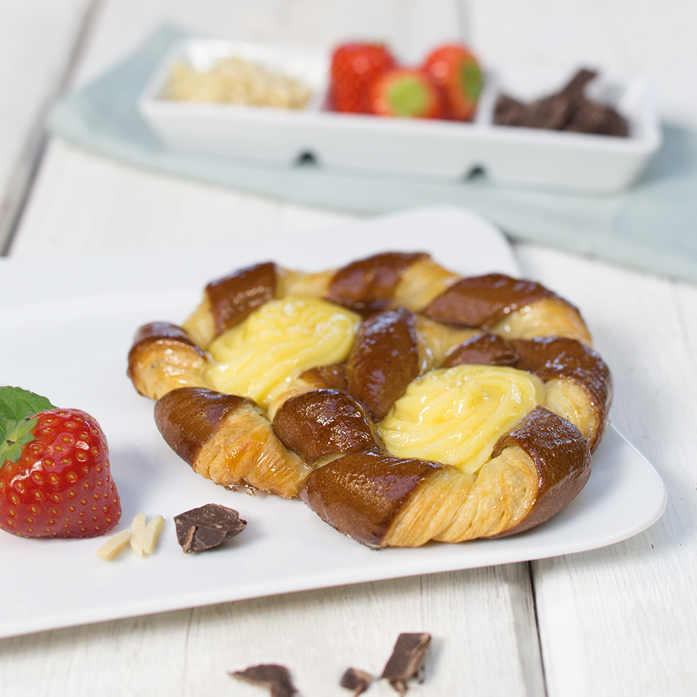 Geflochtenes Gebäck mit Vanillecreme auf weißem Teller