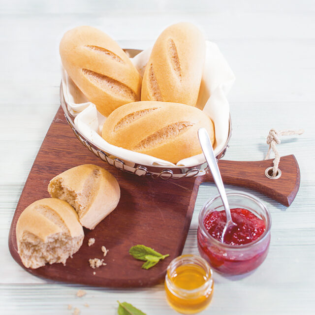 Vier Schneeweizen Brioche, eins in der Mitte zerteilt mit Schälchen mit Marmelade