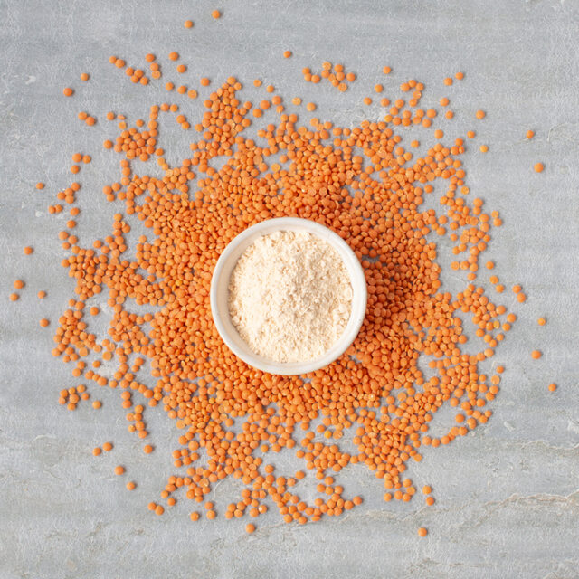 Schale mit rotem Linsenmehl, drumherum rote Linsen