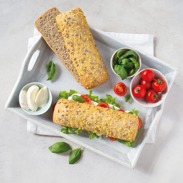 Zwei Gowelltastyprotein Sub Baguette. eins aufgeschnitten, eins belegt mit Tomaten und Mozarella