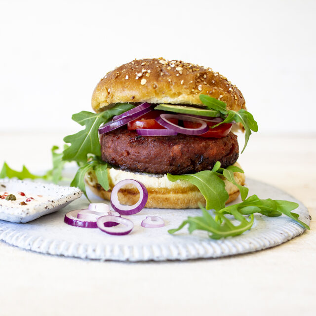 Ein Burger mit Pattie, Zwiebeln, Tomaten und Salat