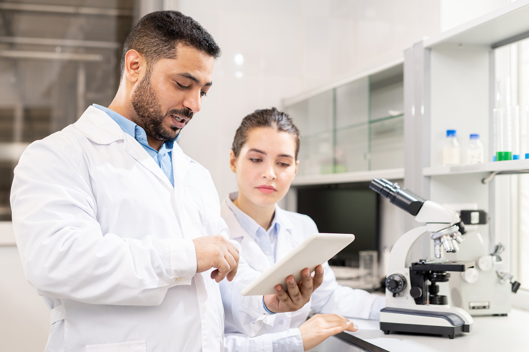 Zwei Personen in weißen Kitteln schauen auf ein Tablet in einem Labor