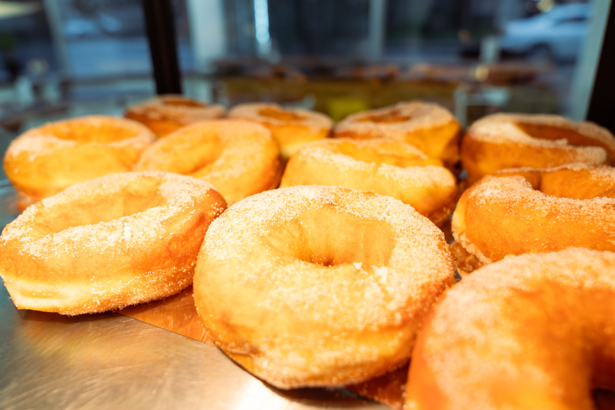 Frisch gebackene, mit Zucker überzogene Donuts, präsentiert auf einer Metalltheke